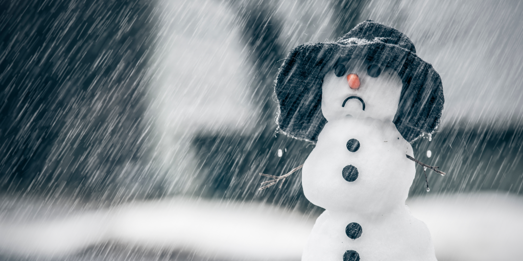 Sad snowman with black hat with wet snow coming down